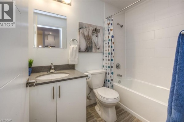 Bedroom with a textured wall, large windows, and a queen-sized bed - 1438 Highland Road W Unit# 502, Kitchener