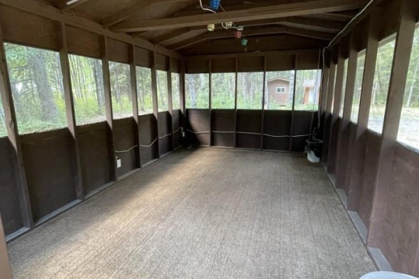 Interior of a screened-in porch with carpeted flooring and multiple windows. - 144 Ahlstrom Drive, Turtle Lake
