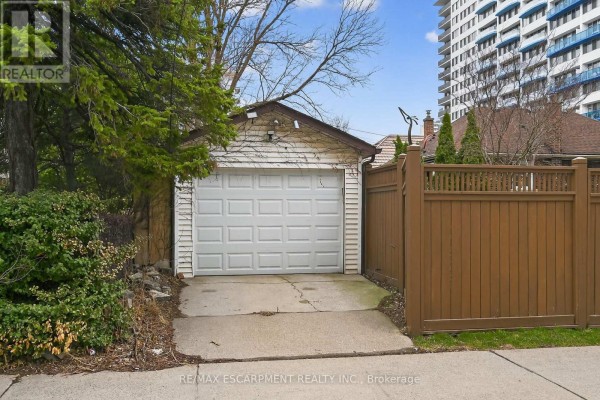 Detached single-car garage with a white sectional door and concrete driveway. - 144 Hunter Street W, Hamilton