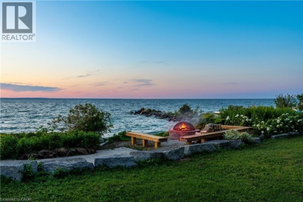 Lakeside fire pit with wooden benches and landscaping at sunset. - 144 Lake Drive E, Georgina