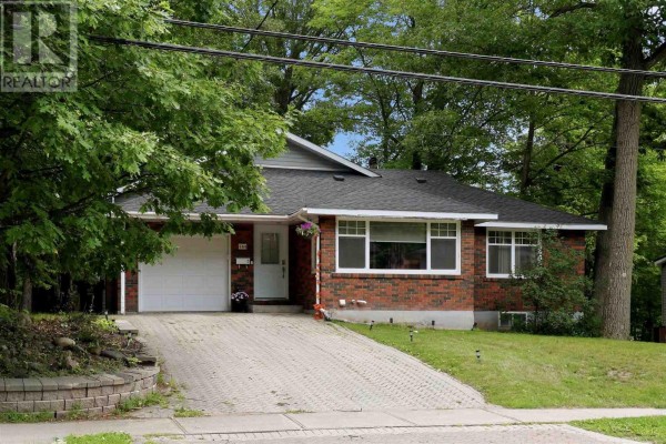 Front exterior of a red brick bungalow with an attached garage and a paved driveway. - 144 Shannon Rd, Sault Ste  Marie