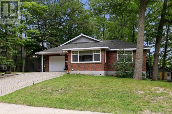 Exterior view of a red brick bungalow with an attached garage, green lawn, and trees. - 144 Shannon Rd, Sault Ste  Marie