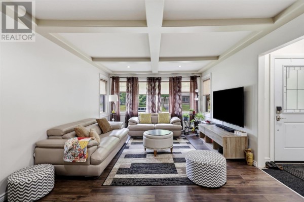 Living room with sectional sofa, coffered ceiling, large TV, and entryway with white door. - 144 Shannon Rd, Sault Ste  Marie
