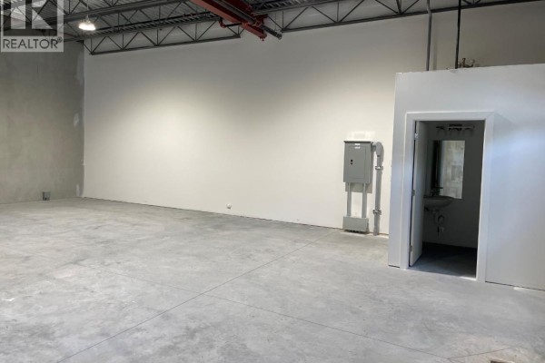 Empty warehouse area with high ceilings and concrete walls. - 1441 Clark Avenue Unit# 104, Penticton