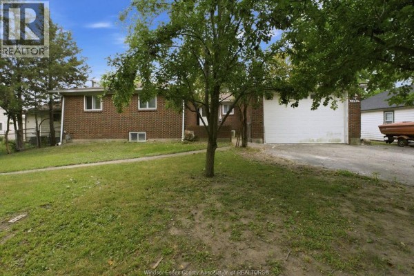Exterior view of a brick bungalow with a lawn and trees in the front yard. - 1441 Heritage Road, Kingsville