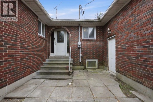 Front entrance with white door, arched brick surround, concrete steps, and adjacent white door. - 1441 Heritage Road, Kingsville