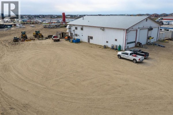 Rear view of a commercial building with trucks and heavy equipment parked nearby. - 14410 102 Street, Rural Grande Prairie No  1, County Of