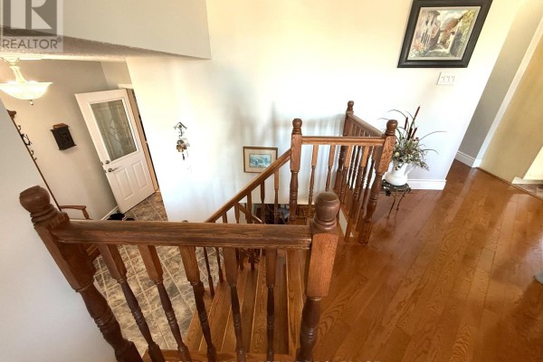Wooden staircase with banister leading down from the upper floor to the main level. - 1442 Windsor Drive, Brockville