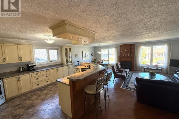 Open concept living area with a kitchen island, fireplace, seating area, and dining space. - 1442 Windsor Drive, Brockville