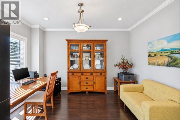 Home office with a wooden desk, hutch, yellow sofa, and artwork. - 1443 40 Street Sw, Calgary