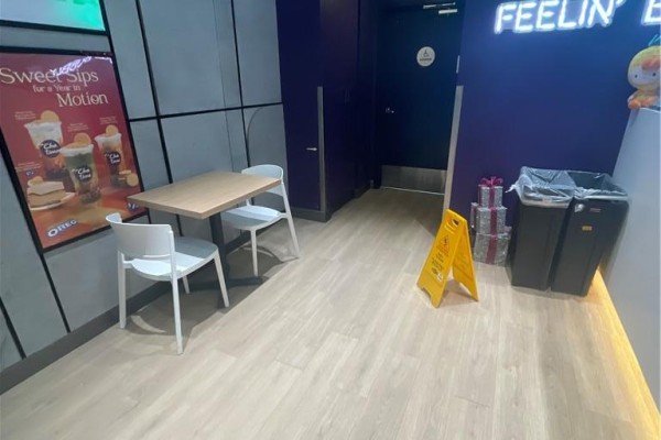 Small dining area with a light wood table, two white chairs, and a wet floor sign. - 1447 Water Street S Unit# 6, Peterborough