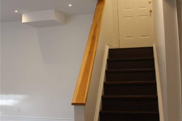 Wooden staircase with dark treads and a light wood handrail leading upwards. - 1449 Ithaca Court, Mississauga