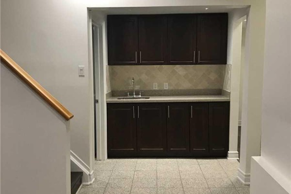 Wet bar with dark wood cabinets, granite countertop, sink, and tiled backsplash on a tiled floor. - 1449 Ithaca Court, Mississauga