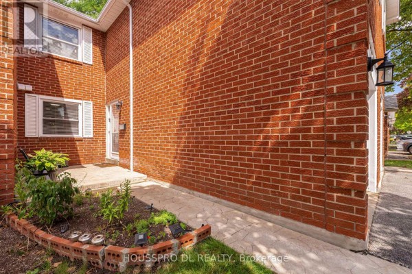 Close-up of townhouse entryway with red brick wall and concrete walkway. - 145 - 10 Bowman Way, Markham