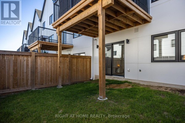 Patio area with grass, wooden fence, and second-floor balcony access. - 145 - 1965 Upperpoint Gate, London South