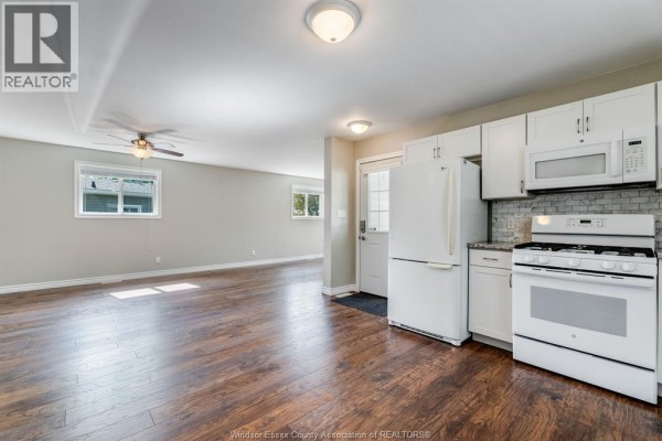 Open concept living area and kitchen with dark wood floors and white cabinets. - 145 Dana, Essex