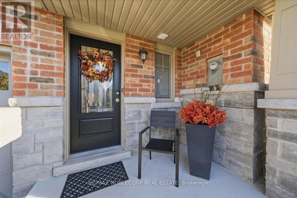 Front door with a decorative wreath and a chair on the covered porch. - 145 Hutchinson Drive, New Tecumseth