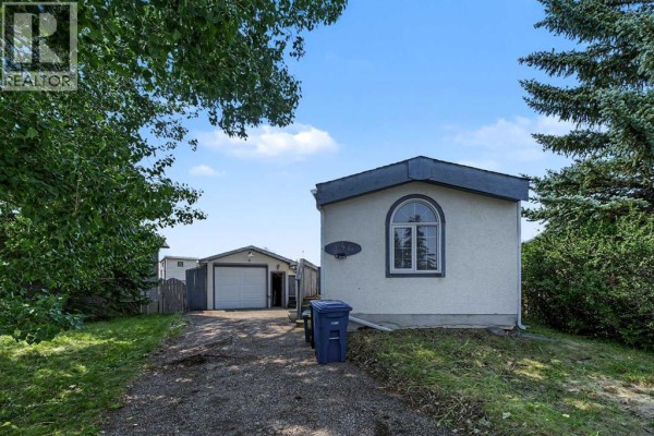 Front view of the mobile home with a driveway and detached garage. - 145 Spring Haven Mews Se, Airdrie