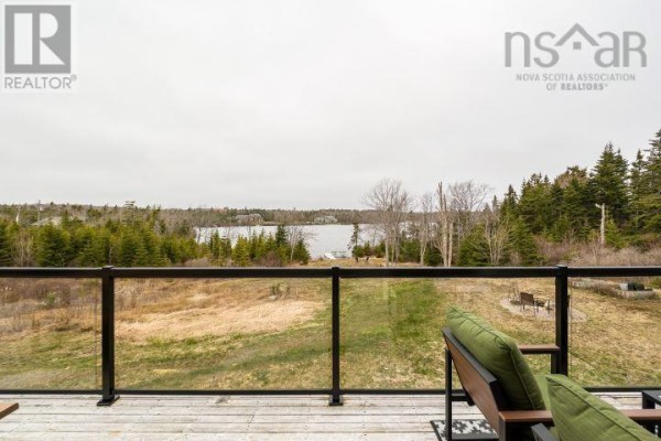 Living room with a grey sectional sofa, coffee table, and large window. - 145 Yellowleaf Lane, Portuguese Cove