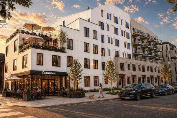 Exterior view of a modern multi-story building with balconies, ground-floor restaurant, and street parking. - 1450 19 Avenue Sw, Calgary