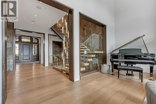 Foyer and entryway of a luxury home featuring a grand piano, floating staircase, and stone accent walls. - 1450 Crystal Creek Drive, Anmore