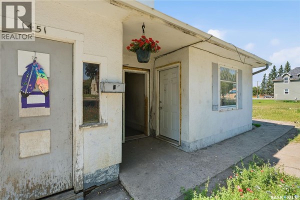 Close-up of the triplex entrance with two doors, a hanging flower basket, and a mailbox. - 1451 101st Street, North Battleford