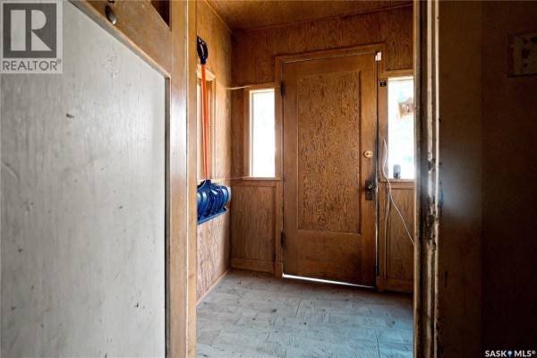 Interior hallway with wood-paneled walls, a wooden door, and two windows. - 1451 101st Street, North Battleford