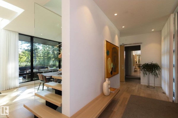 Home entryway with light wood floors, white walls, a floating wooden bench, and abstract art. - 14530 Ravine Dr Nw, Edmonton
