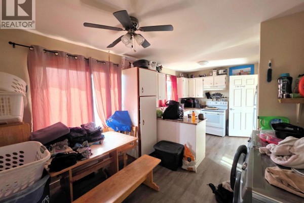 Kitchen with white cabinets, stainless steel appliances, and wood laminate flooring. - 1456-1462 Milburn Avenue, Prince George