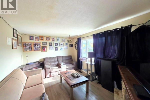 Living room with beige couches, a wood coffee table, and wall decorations. - 1456-1462 Milburn Avenue, Prince George