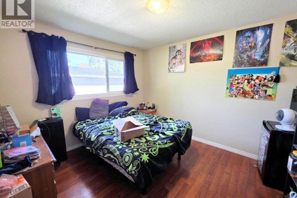 Bedroom with a queen-size bed, hardwood floors, and anime posters. - 1456-1462 Milburn Avenue, Prince George