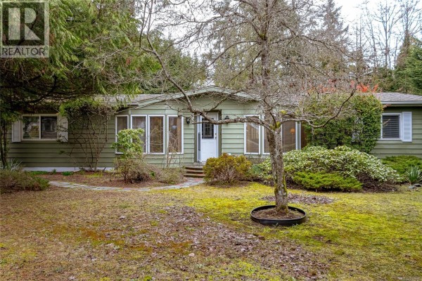 Front view of mobile home with garden area, stone pathway, and shrubs. - 1459 Sunrise Dr, Parksville
