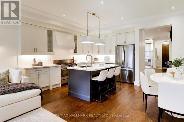 Dining nook with a built-in bench, oval table, white chairs, and two framed ice cream prints. - 145b Bannockburn Avenue, Toronto