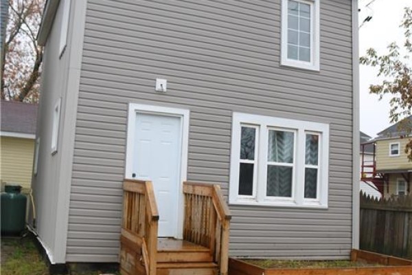 Back exterior of a multi-family home with grey vinyl siding and wooden stairs. - 146 Dominion Street, Moncton