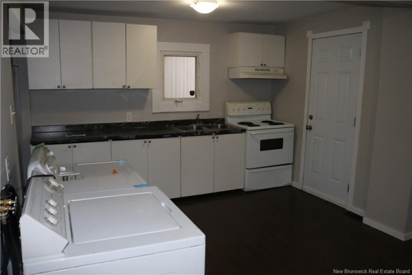 Kitchen with white cabinets, dark countertops, and a white stove and washing machine. - 146 Dominion Street, Moncton