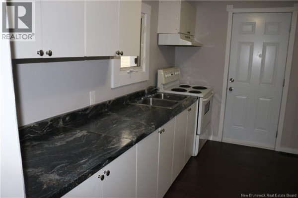 Close-up of a kitchen with white cabinets, dark granite countertops, and a sink. - 146 Dominion Street, Moncton