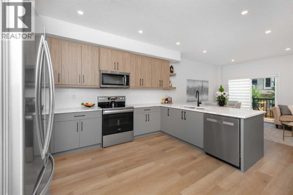 Modern kitchen with light wood and grey cabinets, stainless steel appliances, and island. - 146 Heritage Circle, Cochrane