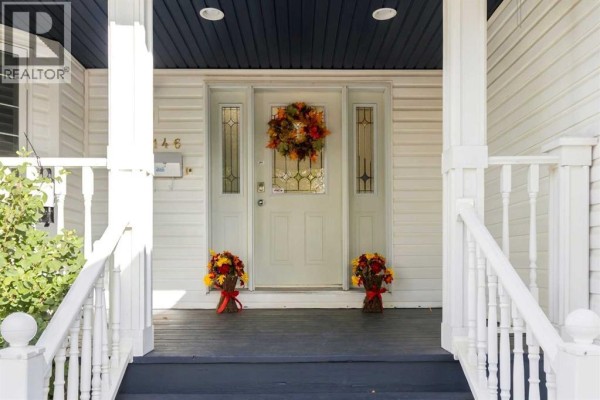Close-up of the white front door with sidelights, glass transom, mail slot, and fall decorations. - 146 Maclaren Crescent, Fort Mcmurray