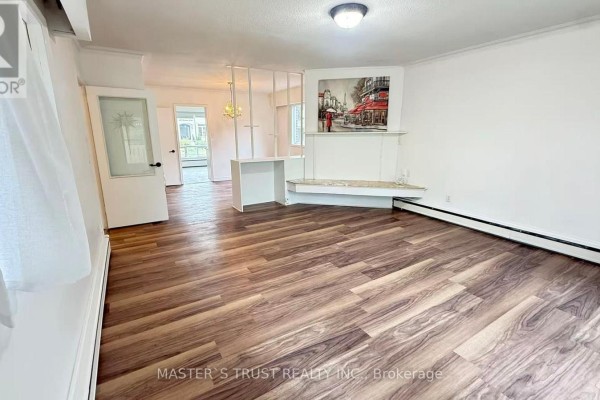 Living room with wood-look flooring, white walls, and decorative fireplace. - 146 Yorkview Drive, Toronto