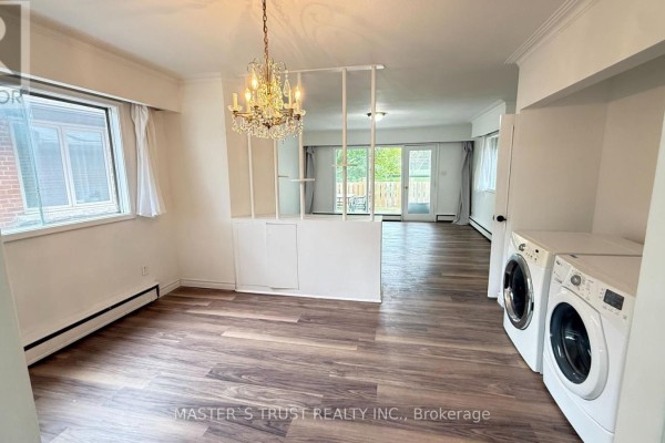 Dining area with chandelier, laundry machines, and view of backyard patio. - 146 Yorkview Drive, Toronto