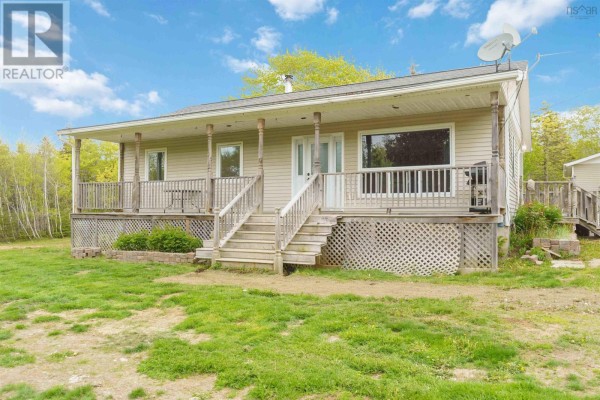 Close-up of the beige bungalow's covered porch with wooden railings and lattice skirting. - 1460 Hampton Mountain Road, Hampton