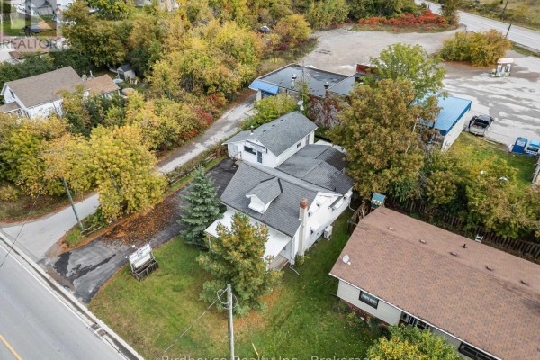 Aerial view of houses and buildings along a street, with trees showing fall colors and a white house in the foreground. - 147 East Street N, Kawartha Lakes