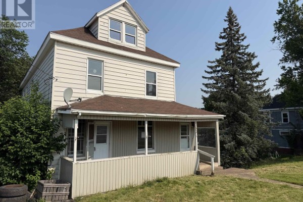 Front view of a light-colored residential house with a porch and mature trees on the side. - 147 Mackay Street, Stellarton