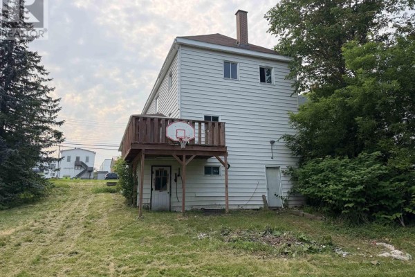 Rear exterior view of a white house with a wooden deck, basketball hoop, and two doors. - 147 Mackay Street, Stellarton