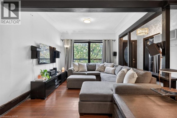 Living room with a large grey sectional sofa, entertainment unit, and large window. - 147 Strachan Street E, Hamilton