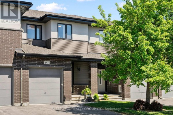 Close-up of townhouse 147 exterior with beige siding, dark brick, and entrance porch. - 147 Westphalian Avenue, Ottawa