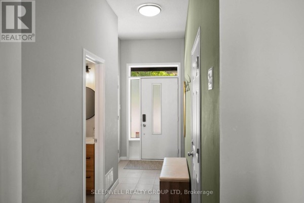 Interior entryway hallway with light grey walls, beige floor tiles, and a white front door. - 147 Westphalian Avenue, Ottawa