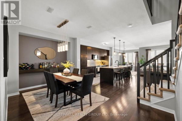 Open concept dining and kitchen area with dark wood cabinets, island with stools, and stairs. - 147 Westphalian Avenue, Ottawa