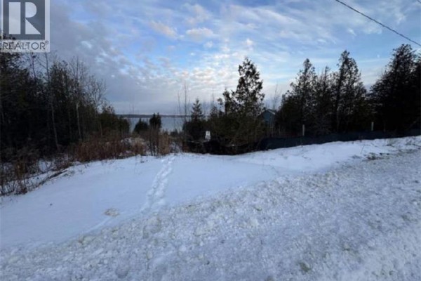 Snowy terrain with a pathway leading towards the water and distant trees. - 147 Wilson Drive, Georgian Bluffs