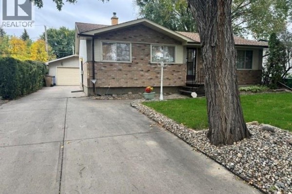 View of the driveway leading to the garage of a brick house. - 147 Woodward Avenue, Regina